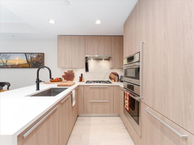 Kitchen featuring light brown cabinetry, a sink, modern cabinets, a peninsula, and recessed lighting | Image 11