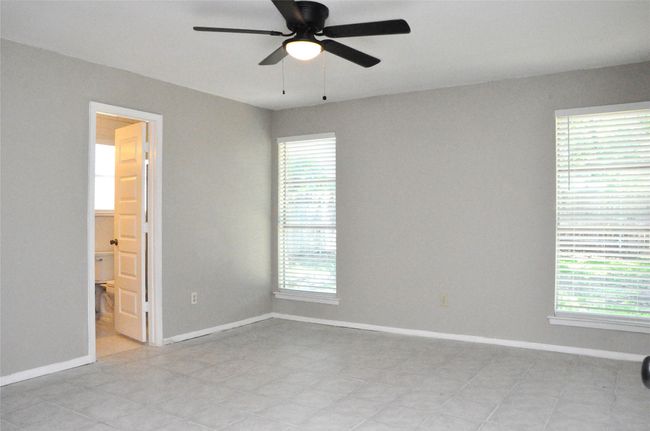 primary bedroom with baseboards, light tile patterned floors, ceiling fan, and plenty of natural light | Image 16