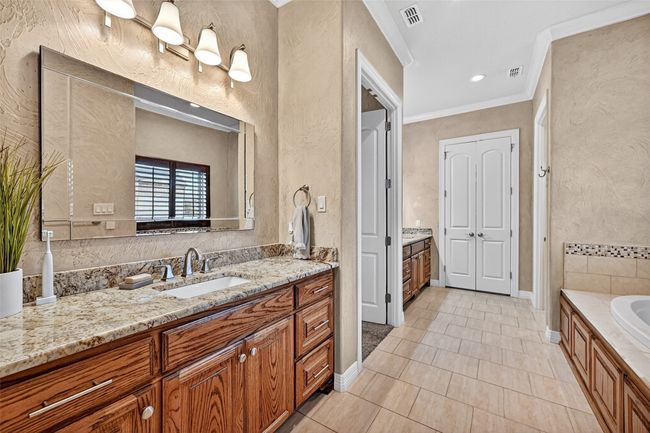 Bathroom with vanity, crown molding, a textured wall, a garden tub, and tile patterned floors | Image 24
