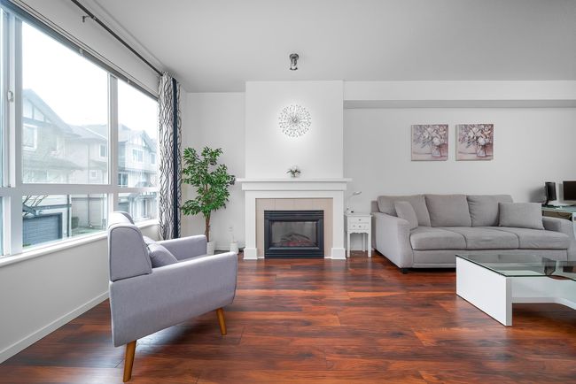 Living area featuring wood finished floors, a tiled fireplace, and baseboards | Image 6