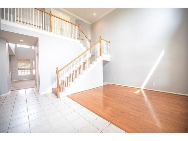 Entryway with stairway, tile patterned floors, baseboards, a towering ceiling, and crown molding | Image 4