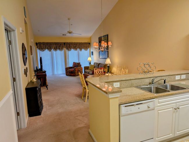 Kitchen featuring open floor plan, high vaulted ceiling, a sink, dishwasher, and light carpet | Image 8