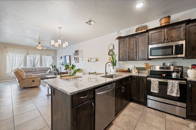 Kitchen with appliances with stainless steel finishes, dark brown cabinets, and a peninsula | Image 11