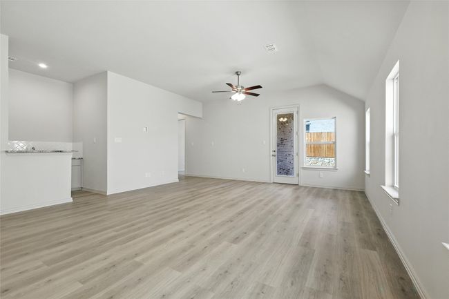 Unfurnished living room featuring ceiling fan, light wood-type flooring, and lofted ceiling | Image 11