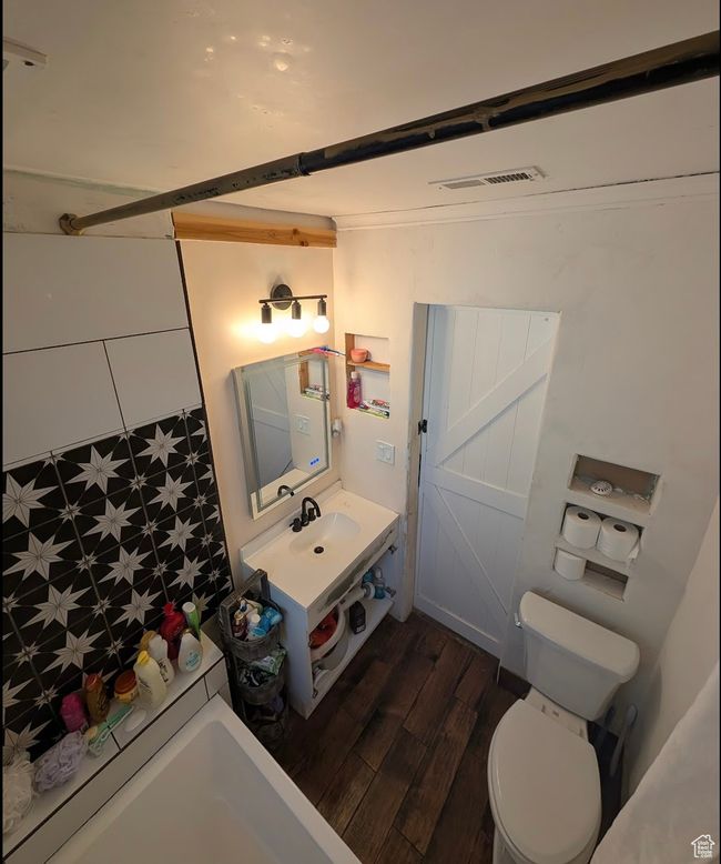 Bathroom with vanity, visible vents, toilet, a shower, and wood finished floors | Image 5