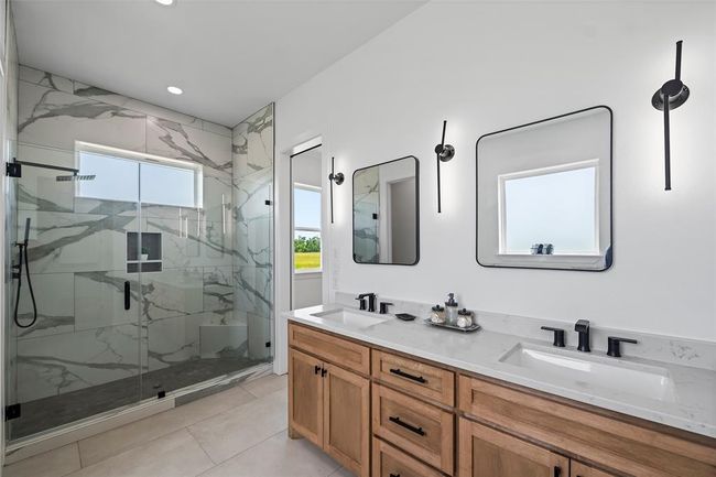 Luxurious primary bathroom featuring a sleek glass-enclosed shower, elegant dual vanities, and modern lighting for a spa-like retreat. | Image 28