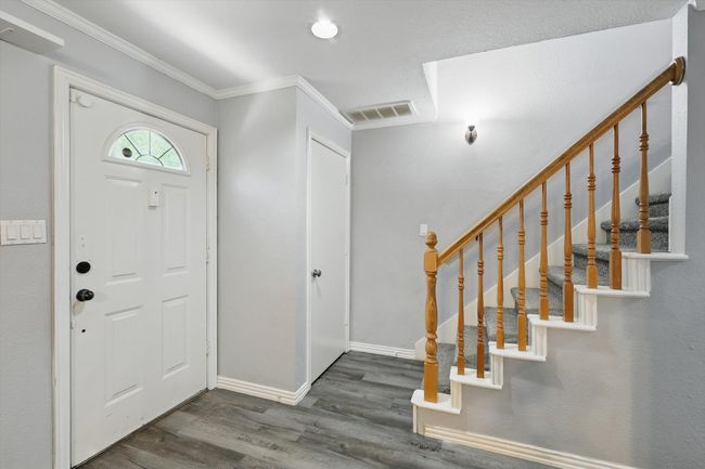 Entrance foyer with wood finished floors, crown molding, and stairway | Image 6