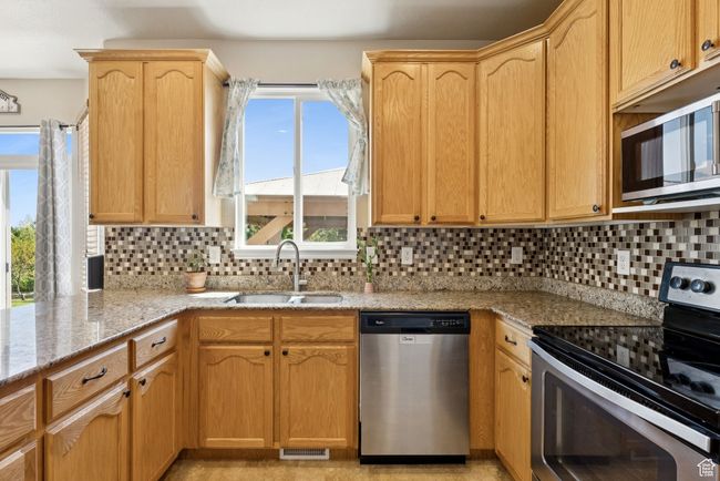 Kitchen with appliances with stainless steel finishes, light stone counters, backsplash, and light brown cabinetry | Image 13