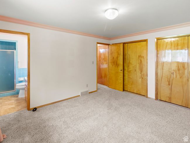 Unfurnished bedroom with carpet flooring, two closets, ornamental molding, ensuite bathroom, and baseboards | Image 14