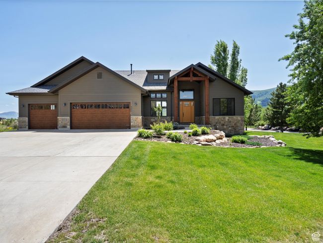View of front of house featuring stone siding, a garage, and a front lawn | Image 56