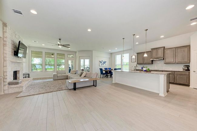 The wood-like tile flooring flows from the Great Room to the island kitchen, dining area and second flexible living area. Abundant natural light floods in through large windows, accentuating the high ceilings and completing this open, inviting entertaining space. | Image 6