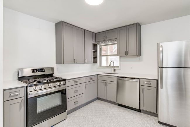 Kitchen featuring stainless steel appliances, gray cabinetry, a sink, and light countertops | Image 5