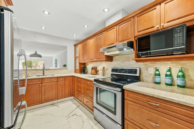 Kitchen with marble finish floor, stainless steel appliances, brown cabinetry, a sink, and under cabinet range hood | Image 10