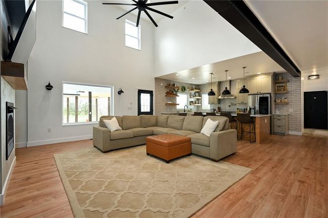 Living area featuring a ceiling fan, light LVP flooring, a high ceiling. | Image 13