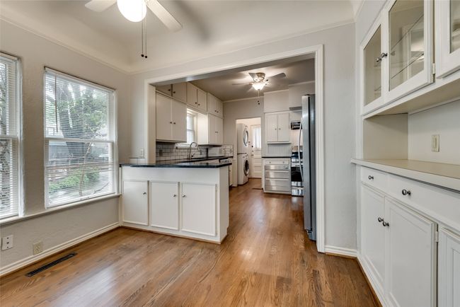 Kitchen with a ceiling fan, white cabinets, and stacked washer / drying machine | Image 11