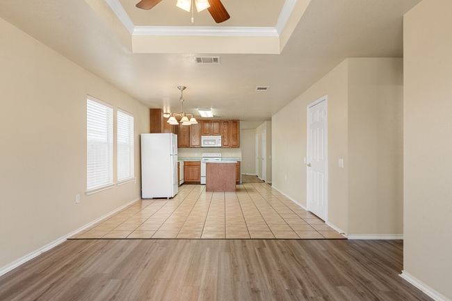 Kitchen with white appliances, light countertops, a chandelier, a tray ceiling, and light wood finished floors | Image 12