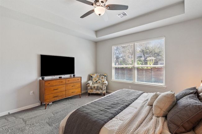 Bedroom featuring light carpet, a tray ceiling, and a ceiling fan | Image 17
