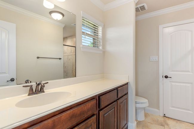 Full bathroom featuring toilet, visible vents, tile patterned flooring, crown molding, and vanity | Image 33