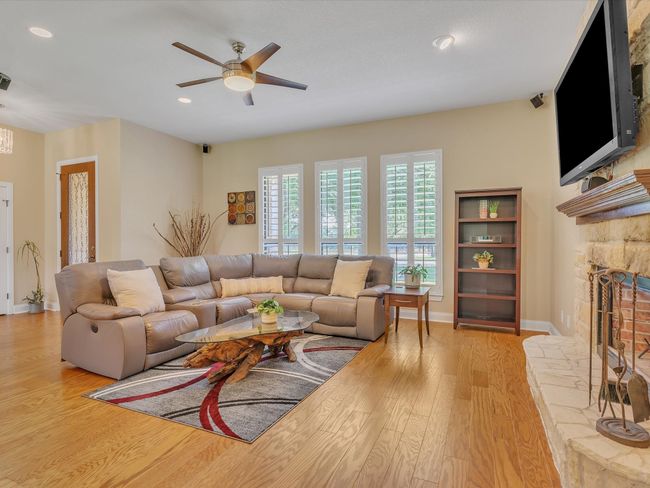 Living area featuring wood finished floors, a fireplace, ceiling fan, baseboards, and recessed lighting | Image 8