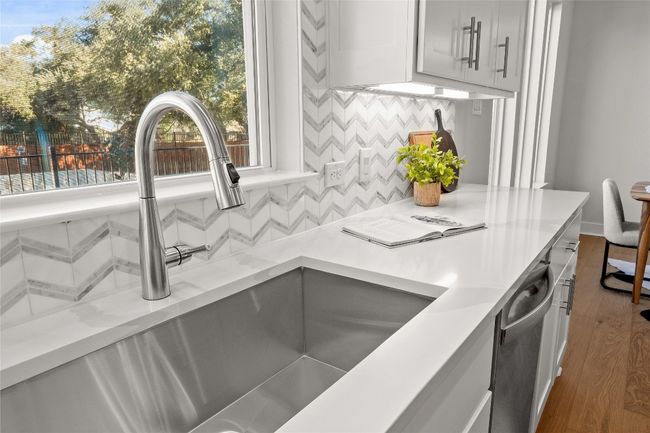 Interior details featuring a sink, backsplash, gray cabinetry, wood finished floors, and light stone​​‌​​​​‌​​‌‌​‌‌​​​‌‌​​‌‌​‌​​​​​‌ counters | Image 14