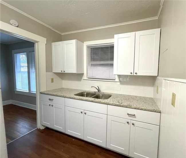 Kitchen with white cabinets, crown molding, a sink, and dark wood-type flooring | Image 4