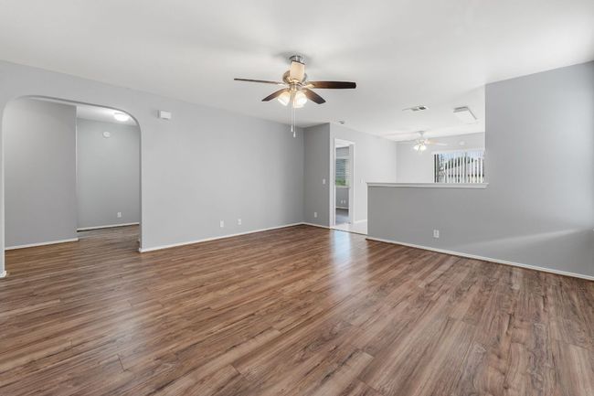 Unfurnished living room with a ceiling fan, arched walkways, and wood finished floors | Image 6