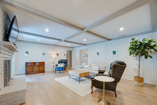 Living room with a decorative wall, a fireplace, light wood finished floors, beamed ceiling, and recessed lighting | Image 10