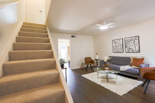 Living area with dark engineered hardwood floors and ceiling fan. | Image 22