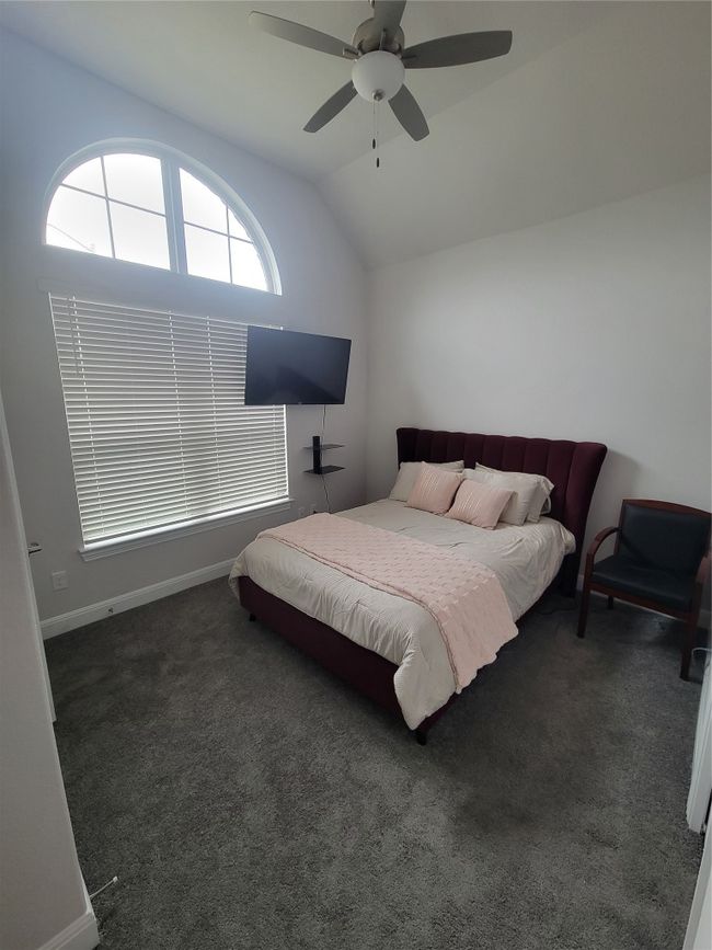 Carpeted bedroom featuring a ceiling fan, baseboards, and vaulted ceiling | Image 7