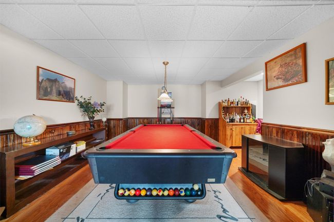 Recreation room with a paneled ceiling, pool table, wainscoting, wood finished floors, and wooden walls | Image 29