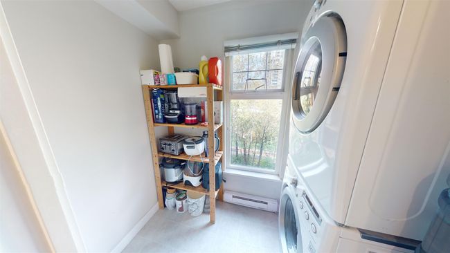Laundry room featuring a baseboard heating unit, a wealth of natural light, stacked washer / drying machine, and laundry area | Image 6