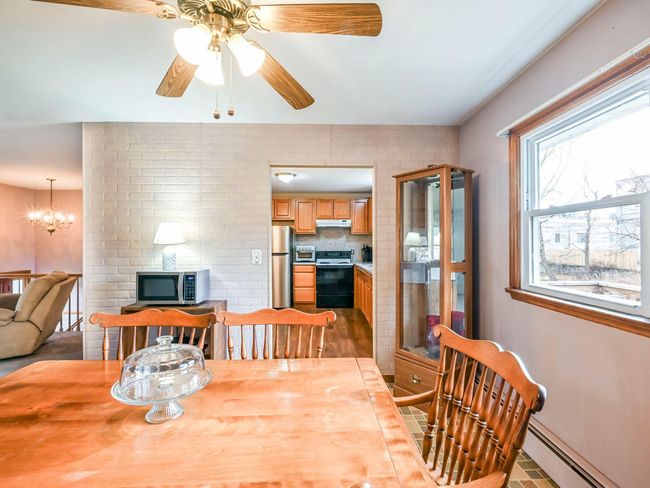 Tiled dining area featuring ceiling fan with notable chandelier and a baseboard heating unit | Image 7