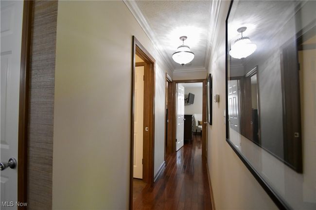 Hall featuring dark wood-type flooring, ornamental molding, and baseboards | Image 13