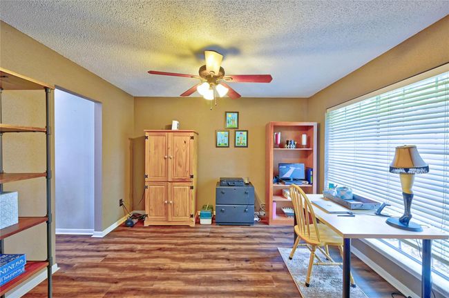 A bright and versatile dining area with ample natural light, it features stylish flooring and a ceiling fan. It is perfect for gatherings or a cozy workspace. | Image 7