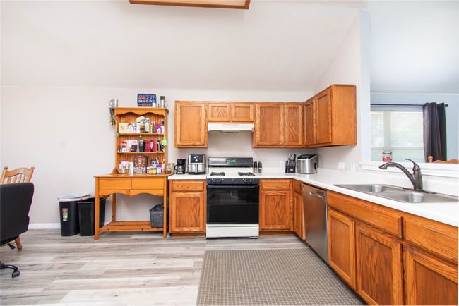 Kitchen featuring gas range oven, vaulted ceiling, under cabinet range hood, dishwasher, and a sink | Image 6