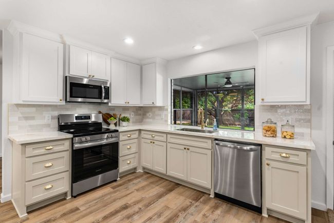 Kitchen with appliances with stainless steel finishes, a sink, decorative backsplash, light wood finished floors, and recessed lighting | Image 11