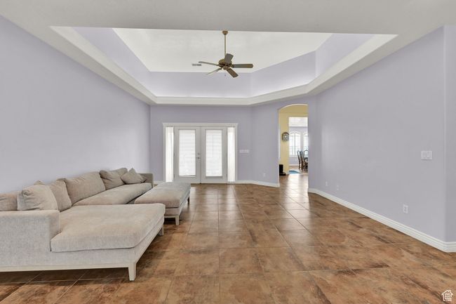 Living area featuring french doors, arched walkways, a ceiling fan, a tray ceiling, and baseboards | Image 12
