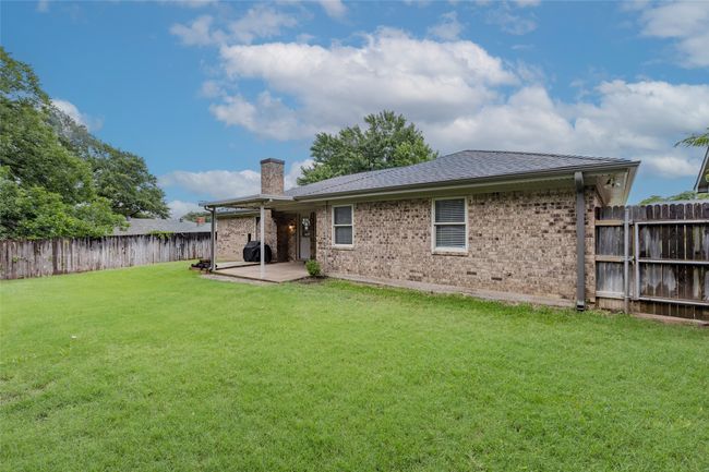 Back of house featuring a chimney, a fenced backyard, brick siding, a patio, and a shingled roof | Image 14