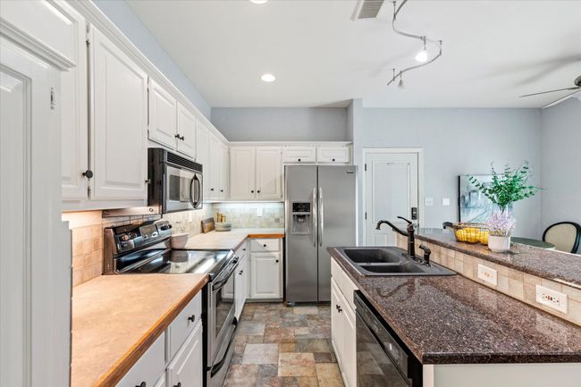 Kitchen featuring stainless steel appliances, tasteful backsplash, a sink, white cabinets, and a kitchen island with sink | Image 9