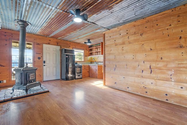 Unfurnished living room with a wood stove, wood walls, and light wood-style flooring | Image 15