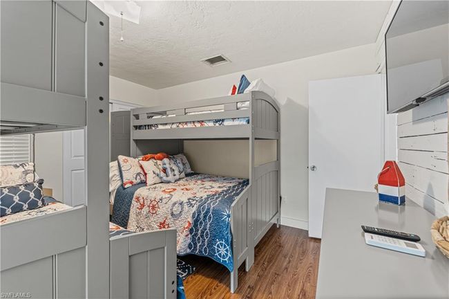 Bedroom with wood finished floors, visible vents, and a textured ceiling | Image 9