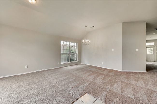 Empty room with carpet flooring, a chandelier, and lofted ceiling | Image 5