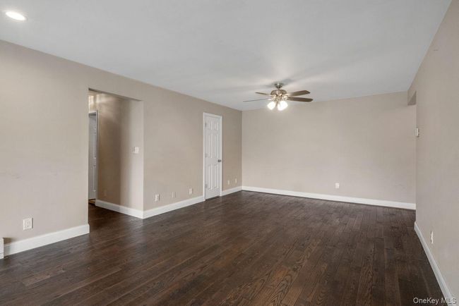 Empty room featuring dark wood-type flooring, baseboards, and ceiling fan | Image 7