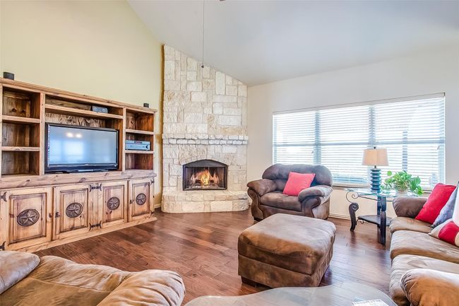 Living area featuring a stone fireplace, high vaulted ceiling, and wood-type flooring. | Image 16