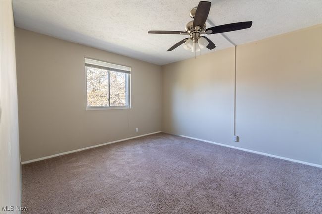 Spare room with carpet, a textured ceiling, baseboards, and ceiling fan | Image 13
