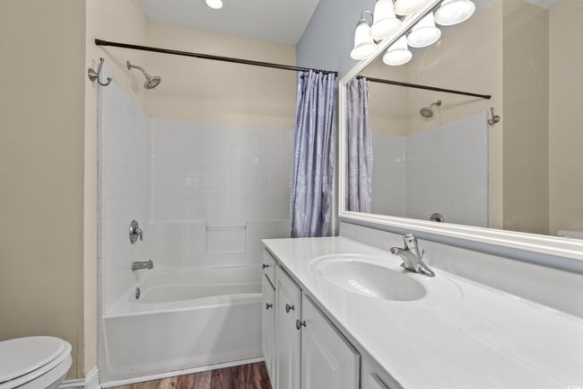 Bathroom featuring wood finished floors, toilet, vanity, and shower / bathtub combination with curtain | Image 15