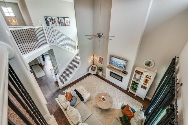 Living area featuring wood finished floors, ceiling fan with notable chandelier, a high ceiling, and baseboards | Image 15