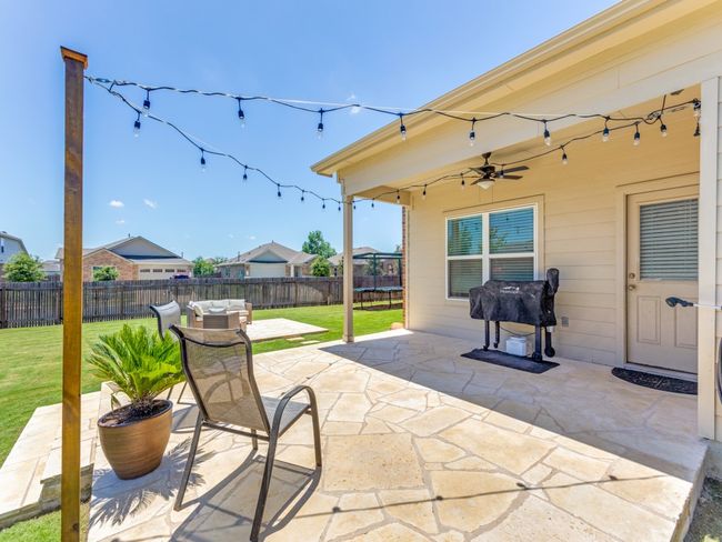 Fenced backyard featuring a trampoline, a patio, ceiling fan, and a grill | Image 30