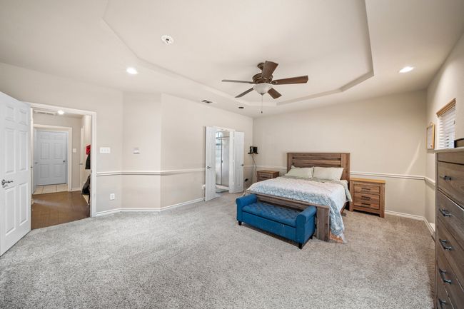 Carpeted bedroom featuring a tray ceiling, baseboards, ceiling fan, and recessed lighting | Image 17
