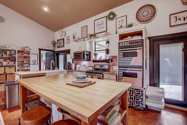 Kitchen featuring wooden counters, stainless steel appliances, a sink, and open shelves | Image 12
